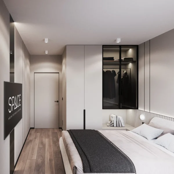 Wardrobe with a black-framed glass section and lighting, bed and door in the bedroom