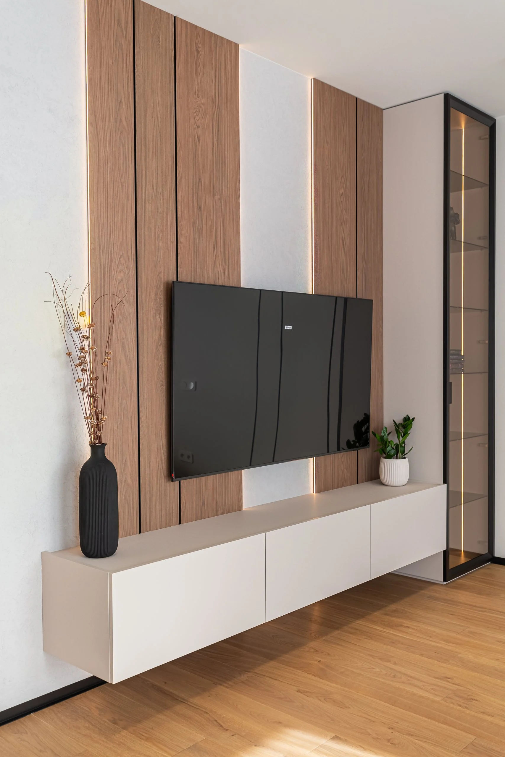 Pionowy widok ściany TV z dębowymi panelami i podświetlaną witryną