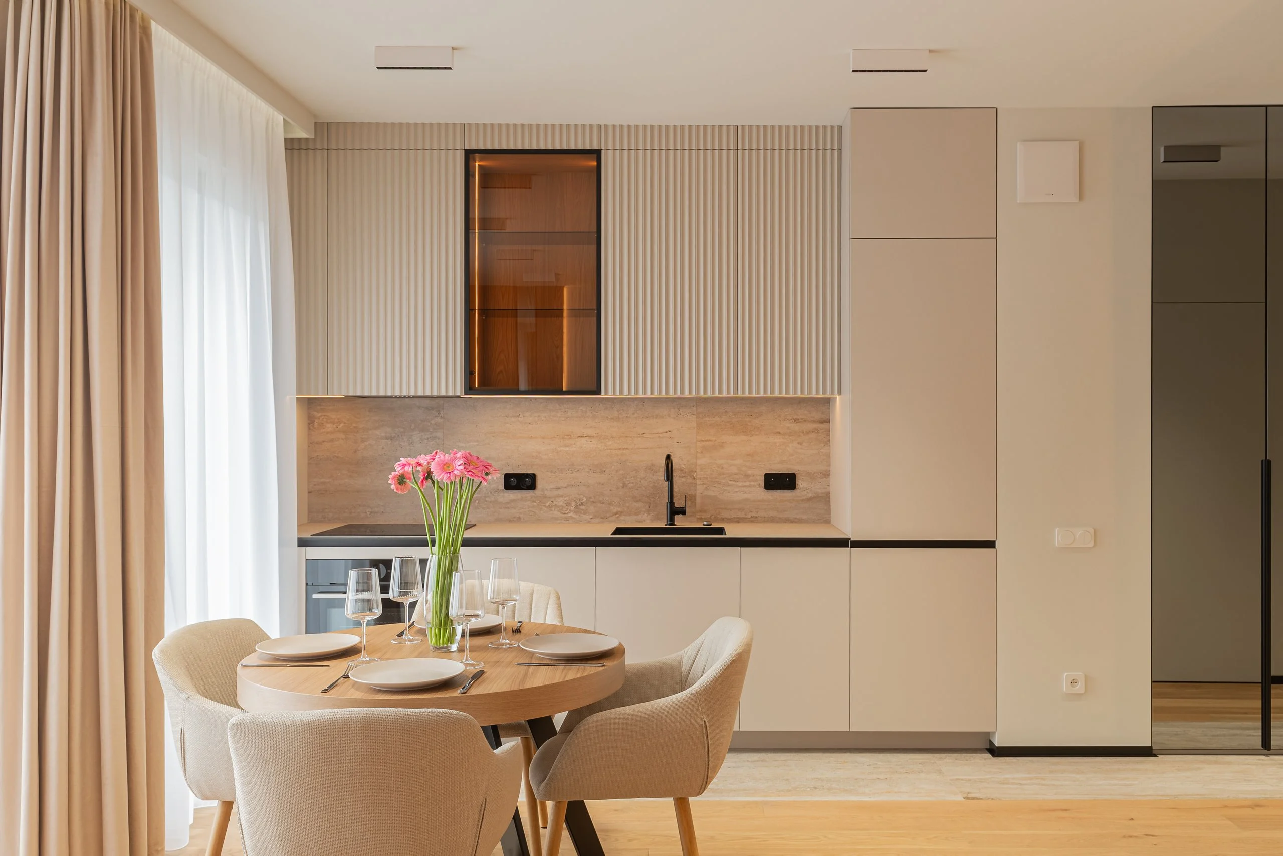 Kuchnia i okrągły stół: fartuch kamieniopodobny, czarna bateria i słupki do sufitu