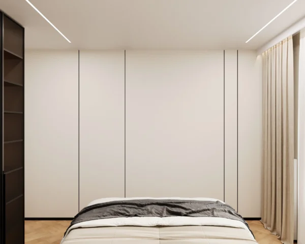 White wall of built-in wardrobes opposite the bed and curtains in a ceiling recess
